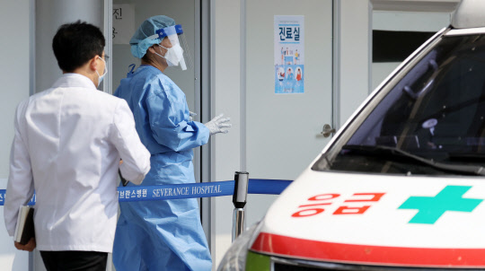 24일 서울 서대문구 세브란스병원 본관 앞에 마련된 안심진료소에서 의료진이 코로나19 검사 관련 업무를 보며 이동하고 있다.  [연합뉴스]